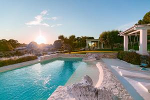 a swimming pool in a house with the sunset in the background at Villa Bernardi in Ostuni +31 photos