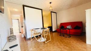 Una sala de estar con una mesa y un sofá rojo. en Studio Cocody 8 LUMIO, en Lumio 16 fotos más