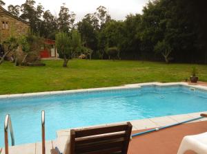 a swimming pool with a chair in a yard at Apartamentos PENAQUENTE in O Porto de Espasante