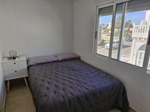 a small bedroom with a bed and a window at Bungalow con barbacoa in Torrevieja