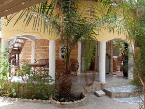 a patio with a table and a palm tree at Guesthouse JUNGLE & OCÉAN ABÉNÉ in Abémé