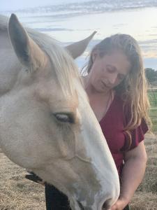 Eine Frau steht neben einem weißen Pferd in der Unterkunft Wellbet Farm in Lincoln