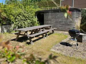 a barbecue grill next to a wooden picnic table at Manoir médiéval art déco - Logis des 3 Artistes in Sevremont