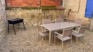 ヌヴェールにあるLa maison de la Loireの建物の前にあるテーブル、椅子4脚、グリル