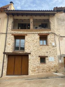 a stone house with a wooden door and a balcony at Casa la luz in La Portellada