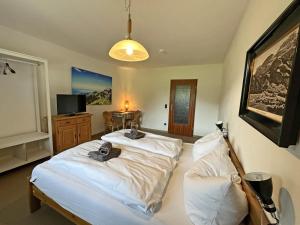 a bedroom with two beds and a table with a television at Gschwendtnerhof App10 KrausW in Aschau im Chiemgau