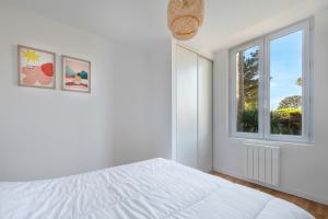 a white bedroom with a bed and a window at Maison rénovée pour 8 - 200m Tharon plage in Tharon-Plage