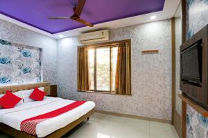 a bedroom with a bed with red pillows and a tv at Hotel O Yatri Yadgar in Mumbai