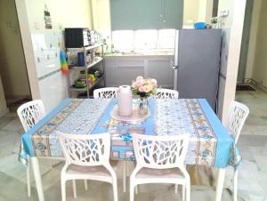 a dining room table with white chairs and a blue table cloth at d'Nur Homestay in Kampong Tanah Merah