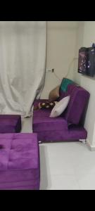 ein Zimmer mit lila Kissen und einem lila Sofa in der Unterkunft وحدة للإيجار في إحدى قرى الساحل الشمالي المميزة in Dawwār Abū Maḩrūs