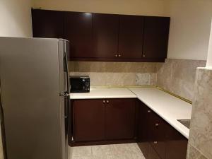 cocina con armarios marrones y nevera de acero inoxidable en Rizstar Suite at Times square, en Kuala Lumpur