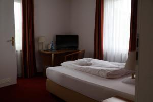 a bedroom with a bed and a desk with a television at Hotel an der Therme in Bad Dürkheim