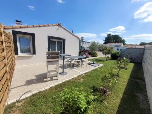 a patio with a table and chairs in a yard at coquet petit studio in Chaillevette