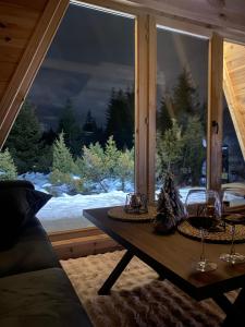 a room with a table in front of a large window at Pine Forrest Uskoci in Žabljak