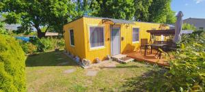 a yellow tiny house in a yard with a deck at Ferienwohnung Sylvia in Neustrelitz