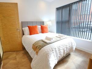a bedroom with a bed with orange pillows and a window at Pass the Keys Mill Conversion Flat Mins from City Bars Shops in Manchester