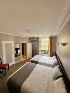 a hotel room with two beds and a window at New Hôtel Gare Du Nord in Paris