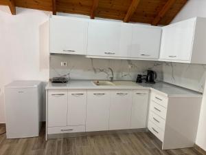 a kitchen with white cabinets and a sink and a refrigerator at P&K apartment Pogradec in Pogradec +12 photos