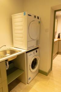 a laundry room with a washing machine and a sink at Luxury 2 Bed Woodland Cottage on Rewilding Estate in Beaminster