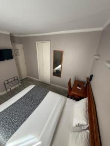 Un dormitorio con una cama, una mesa y un espejo. en New Hôtel Gare Du Nord, en París