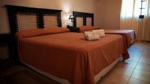 two beds in a room with orange sheets at Hotel Jardín del Paraná in Paso de la Patria