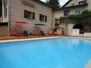 a large swimming pool with chairs and umbrellas next to a building at La Méridienne - Gite Ceusette in Venterol