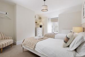 a white bedroom with two beds and a chair at The Smithy in Chipping Norton