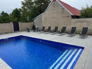 a blue swimming pool with chairs and a brick wall at Penzion U Hujňáků in Rohatec