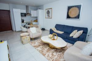 a living room with a blue couch and a table at The Steward Dwellings@Signature in Accra