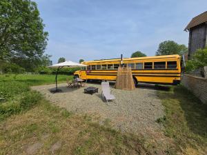 BassengeにあるSchool busのテーブルと傘の隣に駐車された黄色いスクールバス +1枚の写真