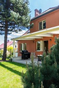 a house with a patio and a tree at Golden Villa Kraków - Stylowa Willa z Ogrodem i Grillem in Węgrzce