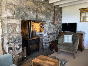 a living room with a stone fireplace and a chair at Pen Y Bryn Bach in Harlech