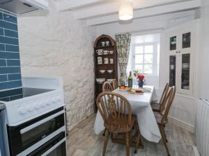 a kitchen with a white table and chairs and a stove at Pen Y Bryn Bach in Harlech
