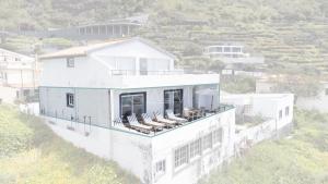Una casa blanca con tumbonas en el balcón. en Esterinha's Ocean Apartment by GALMI, en Jardim do Mar