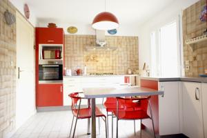 a kitchen with red chairs and a white table at I Melograni 8 personnes in Chomérac