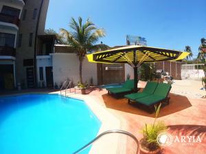 a swimming pool with two green chairs and an umbrella at Aryia Máncora in Máncora
