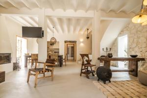 een woonkamer met houten stoelen en een stenen muur bij Finca de los Secretos in Benissa