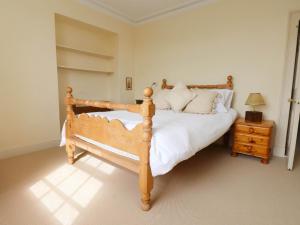 a bedroom with a wooden bed with white sheets and pillows at Flat 3 in Holyhead