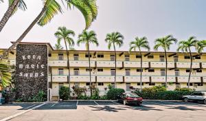 a large building with palm trees in a parking lot at Big Island Kona Magic Sands 113 by Coldwell Banker Island Vacations in Kailua-Kona