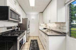 a kitchen with white cabinets and a stove top oven at Big Island Kona Kai D3 by Coldwell Banker Island Vacations in Kailua-Kona