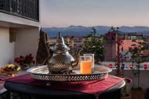 a glass of orange juice on a tray with a tea kettle at Riad Star by Marrakech Riad in Marrakech