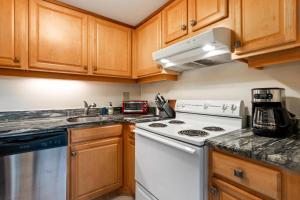 a kitchen with wooden cabinets and a white stove top oven at Big Island Kona Plaza 220 by Coldwell Banker Island Vacations in Kailua-Kona