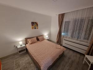 a bedroom with a bed and a window with two lamps at LUX Apartman in Kruševac