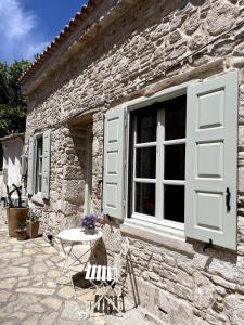 a stone house with a window and a table and chairs at Tigani Loft in Pythagoreio