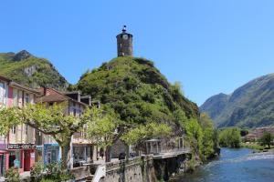 a hill with a lighthouse on top of it next to a river at Hôtel Confort 09 ou HC-09 in Tarascon-sur-Ariège