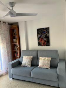 a blue couch in a living room with a ceiling fan at FARO PLAYA in Cullera