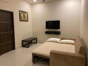 un salon avec un canapé et une télévision à écran plat dans l'établissement LBS Farmstay, à Alāndurai