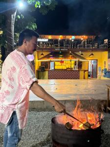Un uomo sta cucinando cibo su una griglia di Hotel Mantra and Adventure a Sauraha