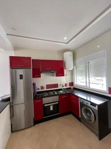 a kitchen with red cabinets and a stainless steel refrigerator at Perle de oued laou in Oued Laou +1 photo
