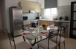 Una cocina con una mesa con sillas y un refrigerador. en Pavilion Apt Cozy 2BR by Elysio, en Paralimni 16 fotos más
